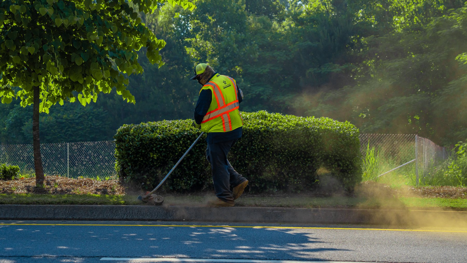 Commercial landscaping maintenance crew trimming along roadside