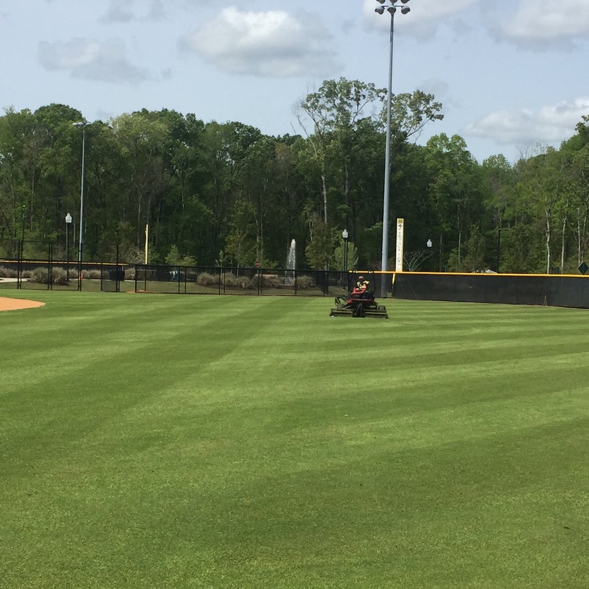 commercial landscape company mows turf at athletic field