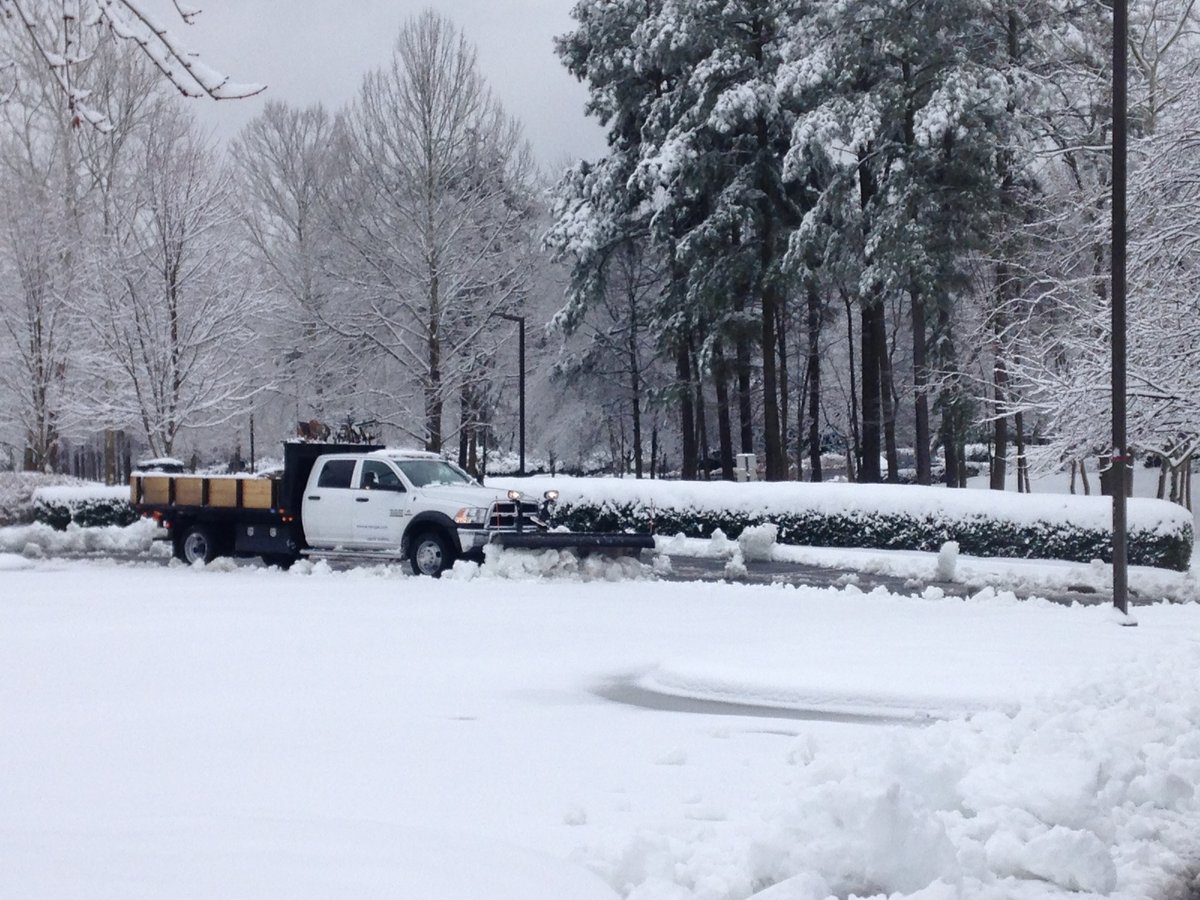 truck snow plowing a commercial parking lot