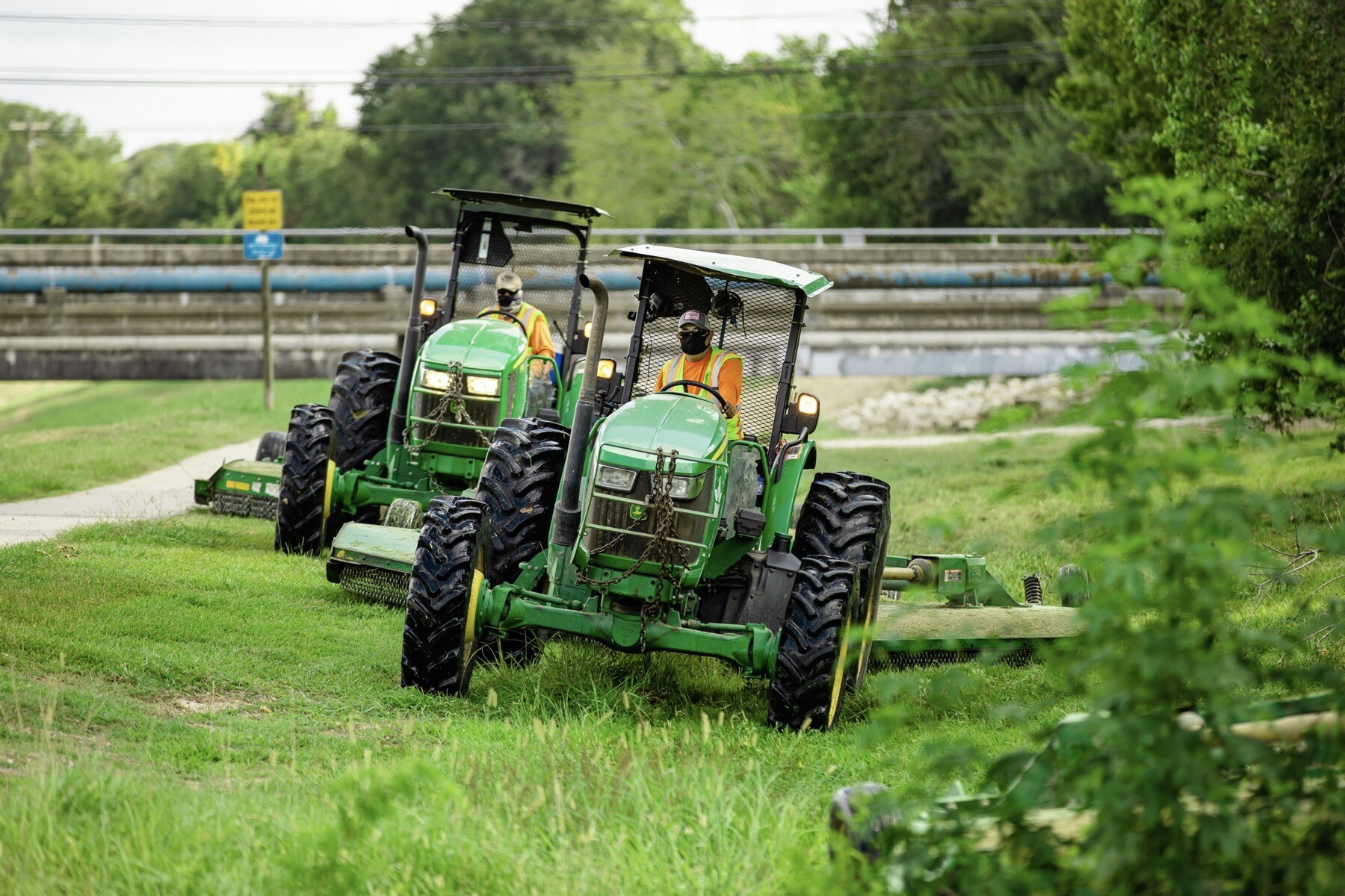tractors mowing near sidewalk